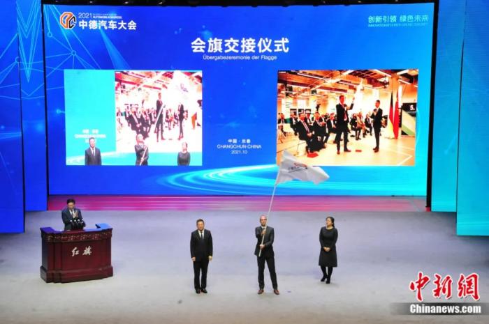 2021年10月19日，2021中德汽車大會在吉林長春舉行。中外汽車領域的專家學者、知名汽車廠商及汽車零部件企業(yè)代表和政府官員，圍繞“創(chuàng)新引領 綠色未來”主題展開探討。圖為中德汽車大會會旗交接儀式。高龍安 攝