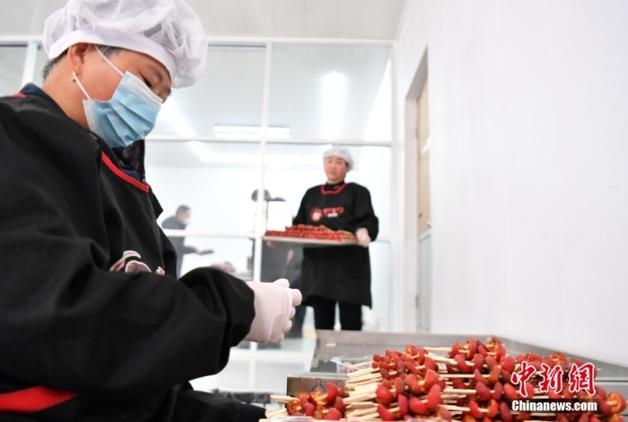 1月18日，雄安新區(qū)大樹劉莊村辛愛(ài)青家中的冰糖葫蘆加工廠，工人正在制作冰糖葫蘆。作為遠(yuǎn)近聞名的“冰糖葫蘆村”，大樹劉莊村制作冰糖葫蘆的歷史已有100多年，全村三分之二的村民都會(huì)這門手藝，吸引不少游客慕名而來(lái)。 中新社記者 韓冰 攝