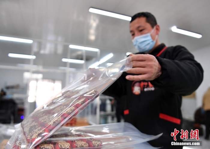1月18日，雄安新區(qū)大樹劉莊村辛愛(ài)青家中的冰糖葫蘆加工廠，工人正對(duì)冰糖葫蘆半成品進(jìn)行真空塑封。作為遠(yuǎn)近聞名的“冰糖葫蘆村”，大樹劉莊村制作冰糖葫蘆的歷史已有100多年，全村三分之二的村民都會(huì)這門手藝，吸引不少游客慕名而來(lái)。 中新社記者 韓冰 攝